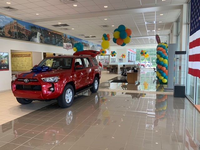Colourful balloons placed around a new car showroom. They only take away from the cars on display. Merchandising in your showroom is more than just balloons.