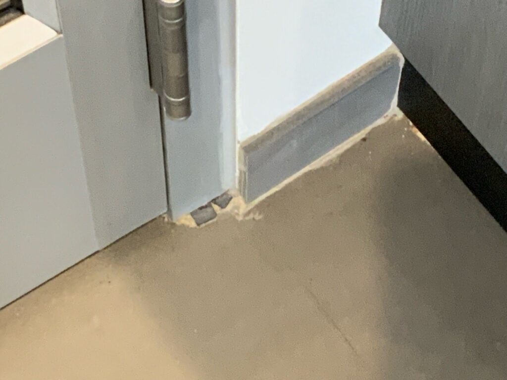 Metal door frame with exposed pieces at the floor and very poor grout work. The Devil is in the details