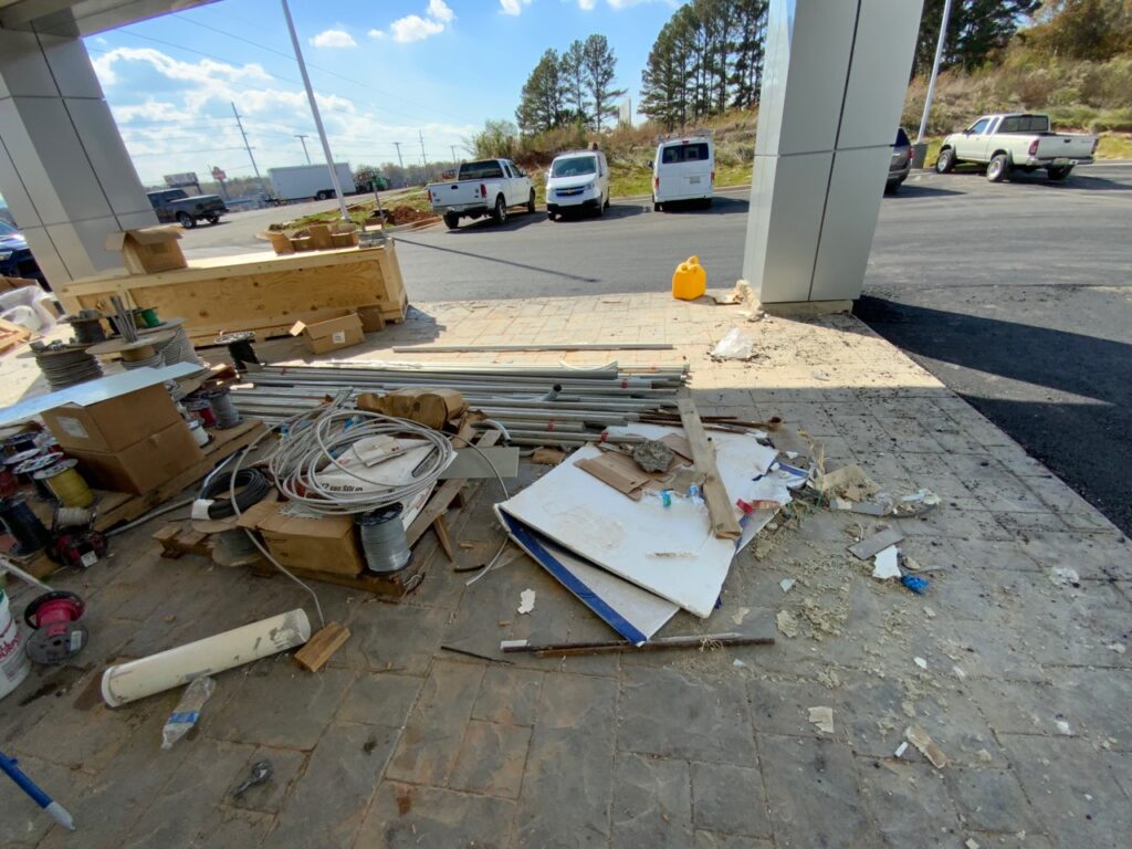 A big mess of garbage and construction materials outside a dealership