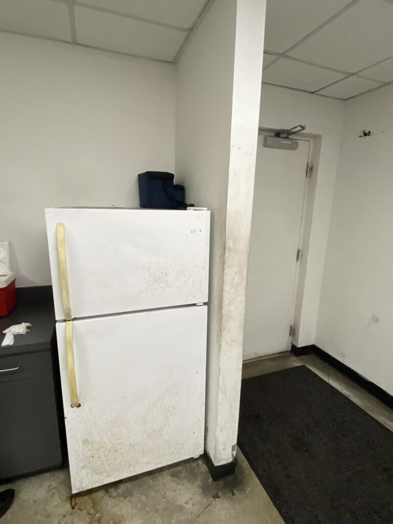 Technician break room with dirty walls and fridge. Don’t Forget the Back of House Staff While Planning Your Next Facility Project