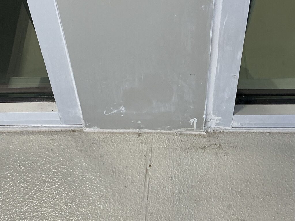 Messy and misaligned caulk installation between two exterior windows. Caulking has quietly replaced craftsmanship.